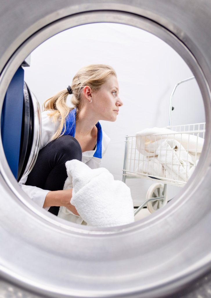 Operatoare încarcă rufe într-o mașină de spălat compactă Electrolux Professional